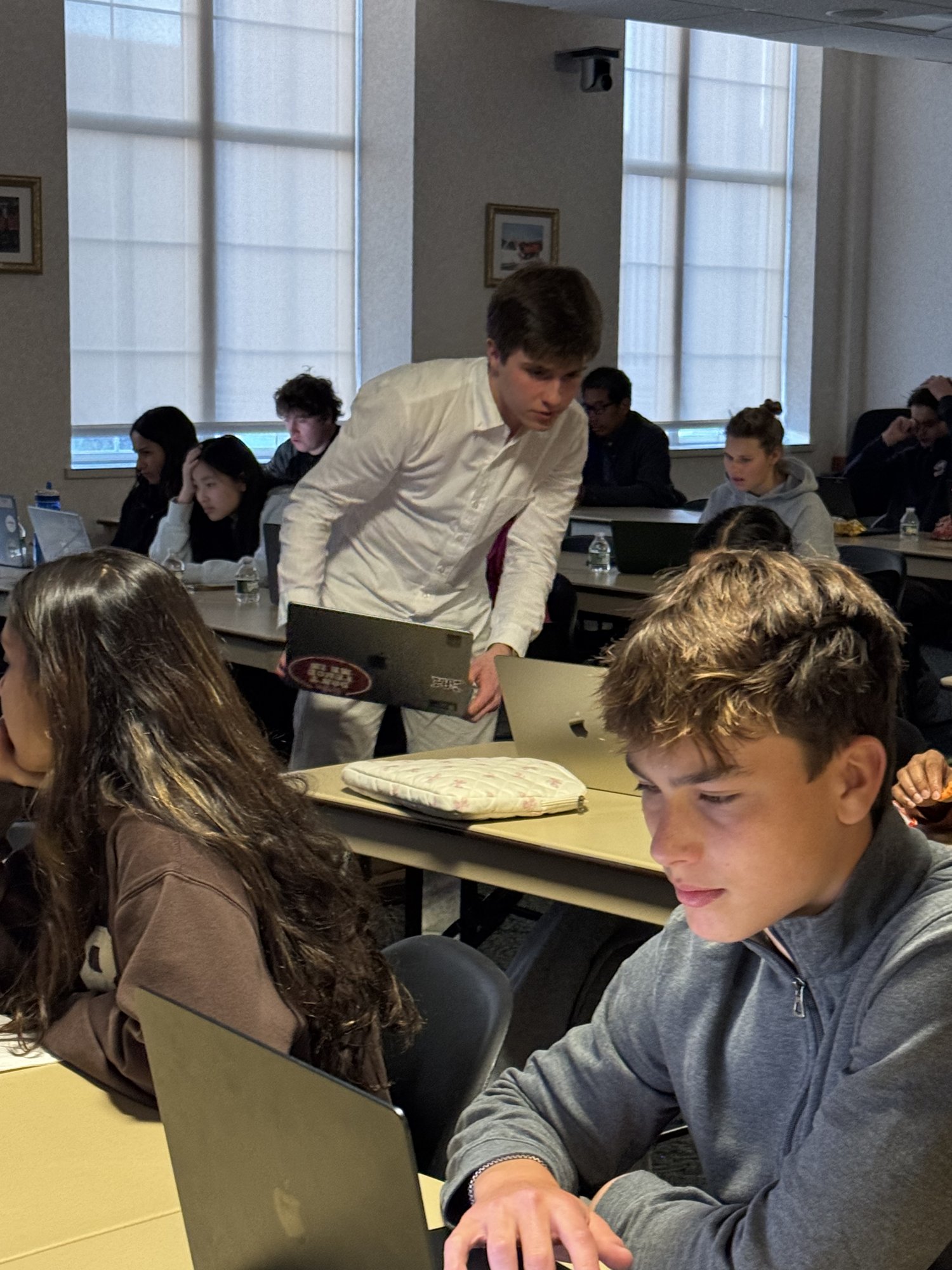 A student running the workshop notebook on his own laptop while classmates work behind him